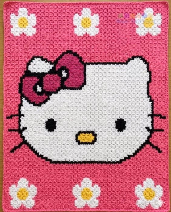 Cute Hello Kitty C2C crochet blanket shown in a full, clear overhead view, featuring a large white Hello Kitty face with a textured dark pink bow on a bright pink background surrounded by white and yellow flowers. Original design created by Ariana Wimsett at MagicYarnPixels.com