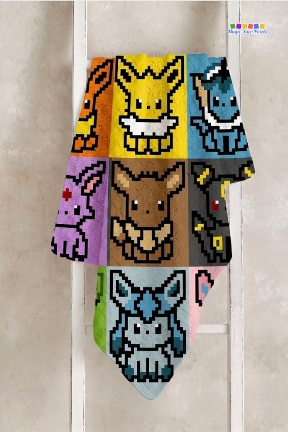 An Eeveelution-themed pixel art crochet blanket hanging vertically over the rungs of a white wooden ladder against a neutral wall. The blanket prominently displays its central panels, featuring pixelated depictions of Jolteon, Eevee, and Glaceon stacked vertically down the middle, flanked by the other colorful Pok&eacute;mon squares. A small logo sits in the top right corner. Original design by Ariana of MagicYarnPixels.