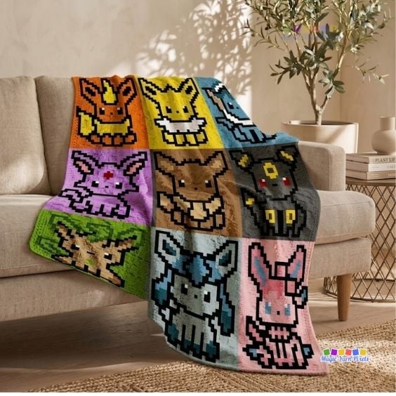 A corner-to-corner (C2C) crochet blanket draped over the arm of a beige fabric couch in a brightly lit living room. The blanket showcases a 3x3 grid layout of pixelated Pok&eacute;mon characters representing the Eevee evolutions: Flareon, Jolteon, Vaporeon, Espeon, Eevee, Umbreon, Leafeon, Glaceon, and Sylveon, each centered in a brightly colored square panel. A small Magic Yarn Pixels logo is visible in the bottom right corner. Original design by Ariana of MagicYarnPixels.