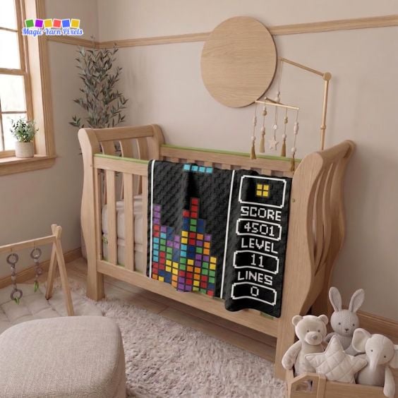 Retro Arcade Blocks C2C crochet blanket draped over a wooden crib in a nursery, featuring colorful pixel blocks and a retro arcade game display. Original design by Ariana of MagicYarnPixels.