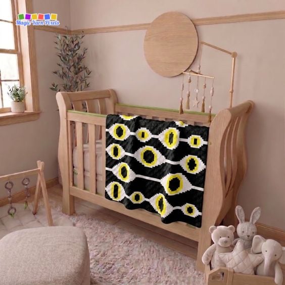 Witchcraft Evil Eye crochet baby blanket draped over a wooden crib, featuring repeating evil eye motifs in black, white, and yellow. Original design by Ariana of MagicYarnPixels.