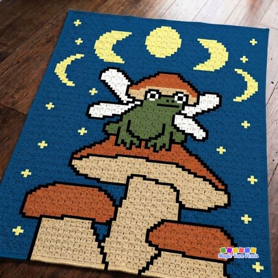 Fairy Frog C2C crochet blanket with a green frog, fairy wings, mushrooms, moon, and stars. Original design by Ariana of MagicYarnPixels.