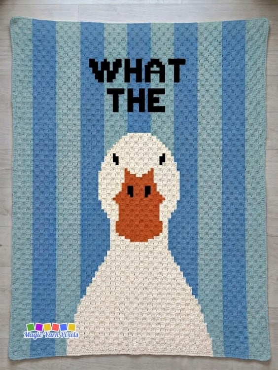 Finished C2C crochet blanket laid flat on a light wood floor featuring a large white duck with an orange bill, blue vertical stripes, and bold black text reading "WHAT THE" across the top. The MagicYarnPixels logo appears in the lower corner. Original design by Ariana of MagicYarnPixels.